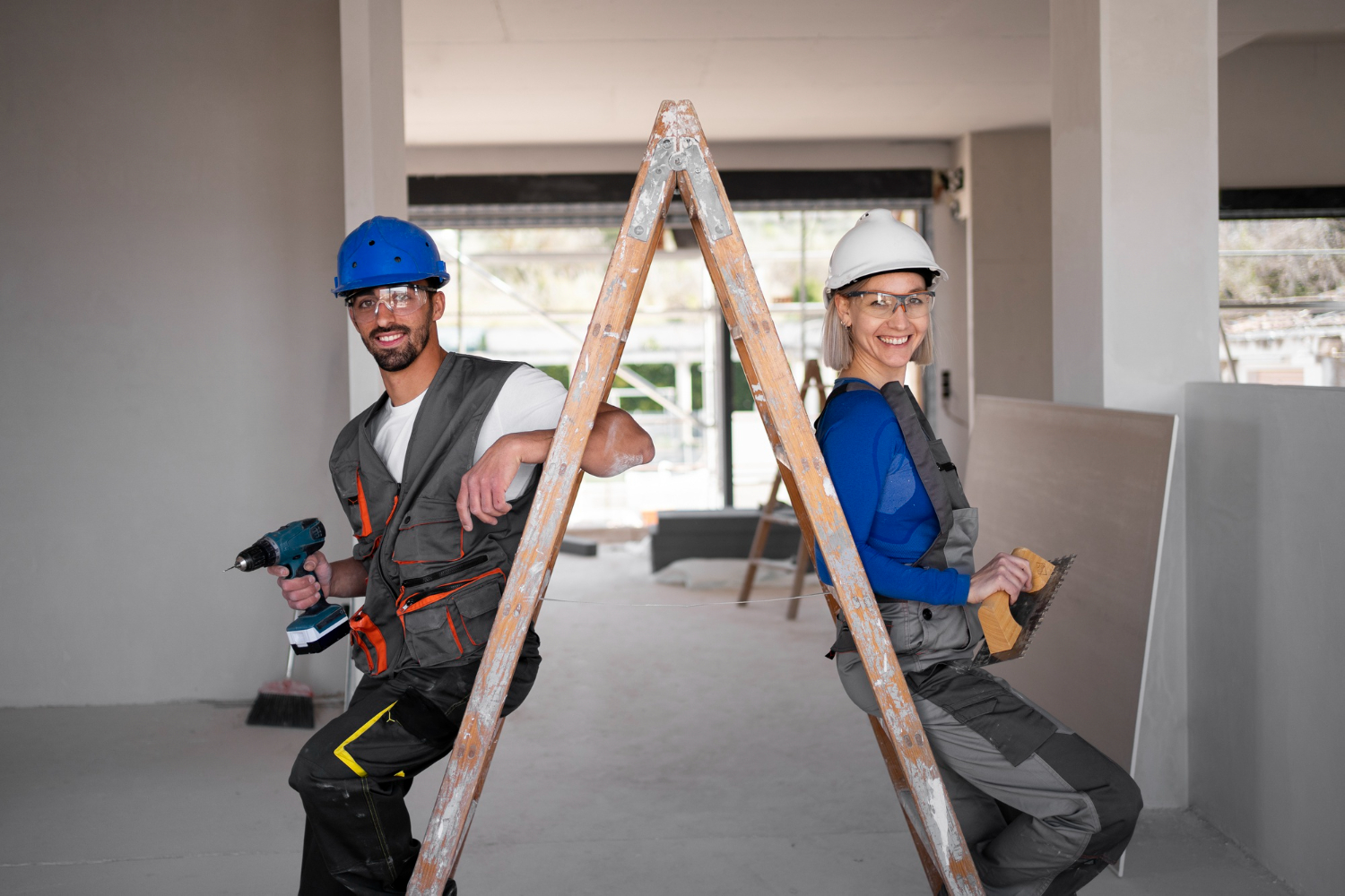 Two construction workers, one male and one female, lean against opposite sides of a ladder. Both wear hard hats and safety vests. The man with a power drill and the woman holding a sanding tool are focused on their renovation tasks in a partially constructed building, ensuring everything checks off the list.